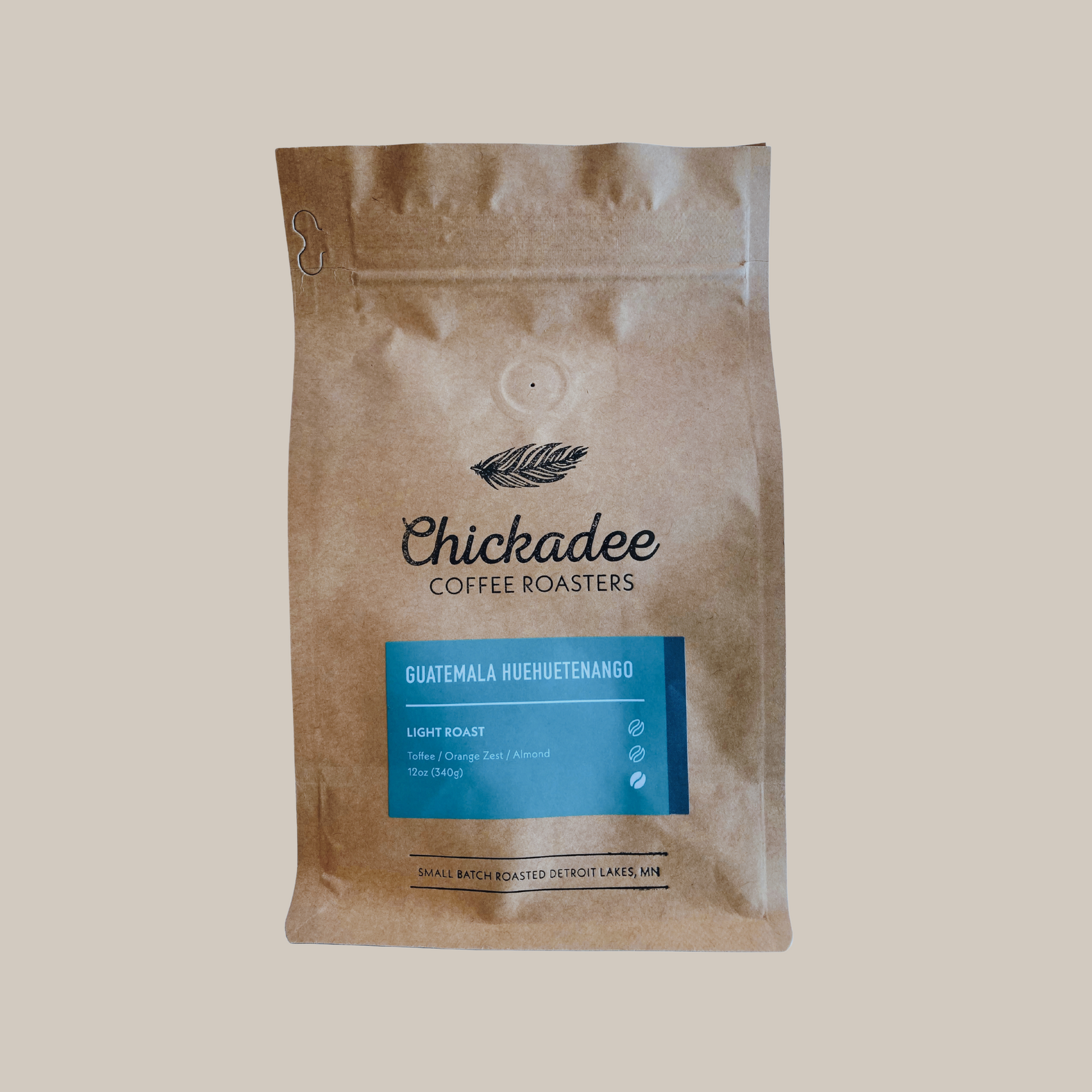 A brown Chickadee Coffee Roasters bag of Guatemala Huehuetenango coffee stands upright, with a blue label highlighting this light roasts toffee notes, set against a plain background.