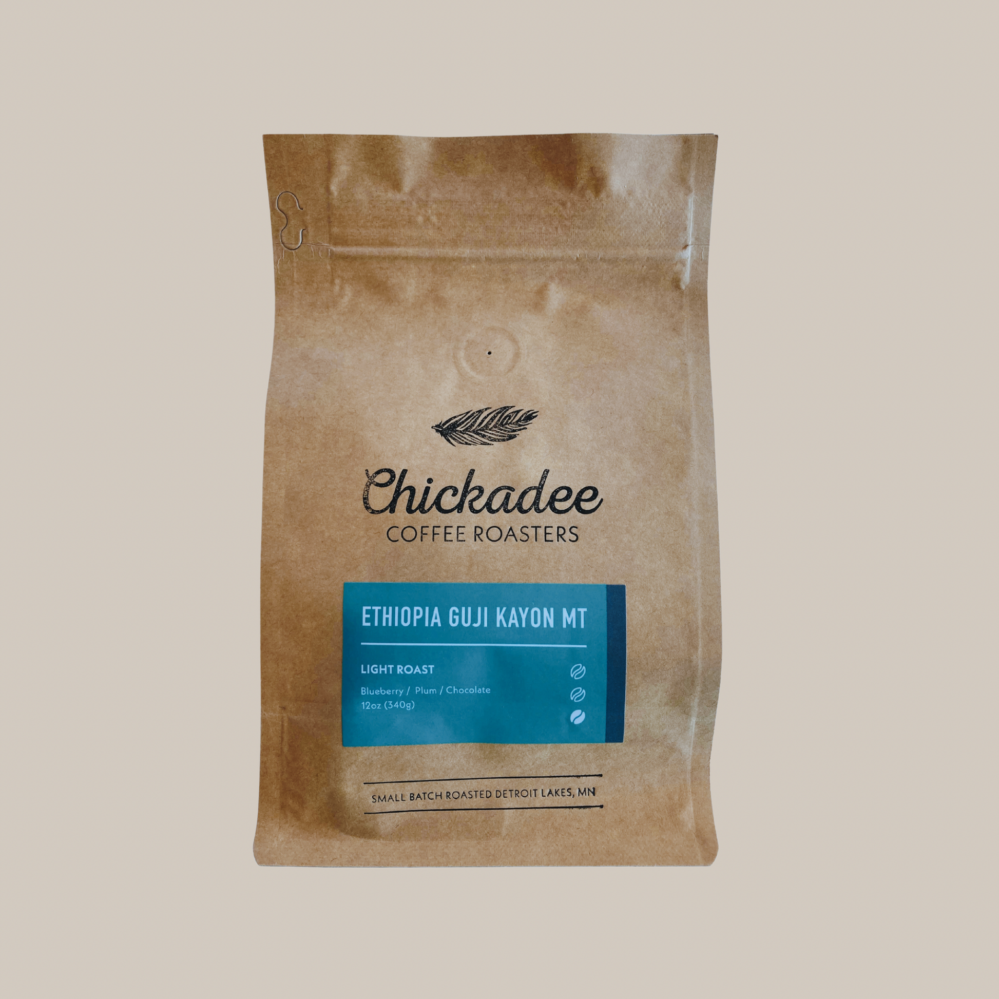 A brown bag of Chickadee Coffee Roasters Ethiopia Guji Kayon Mt light roast coffee features a blue label, black leaf logo, bright blueberry notes, and is small batch roasted in Detroit Lakes, MN.