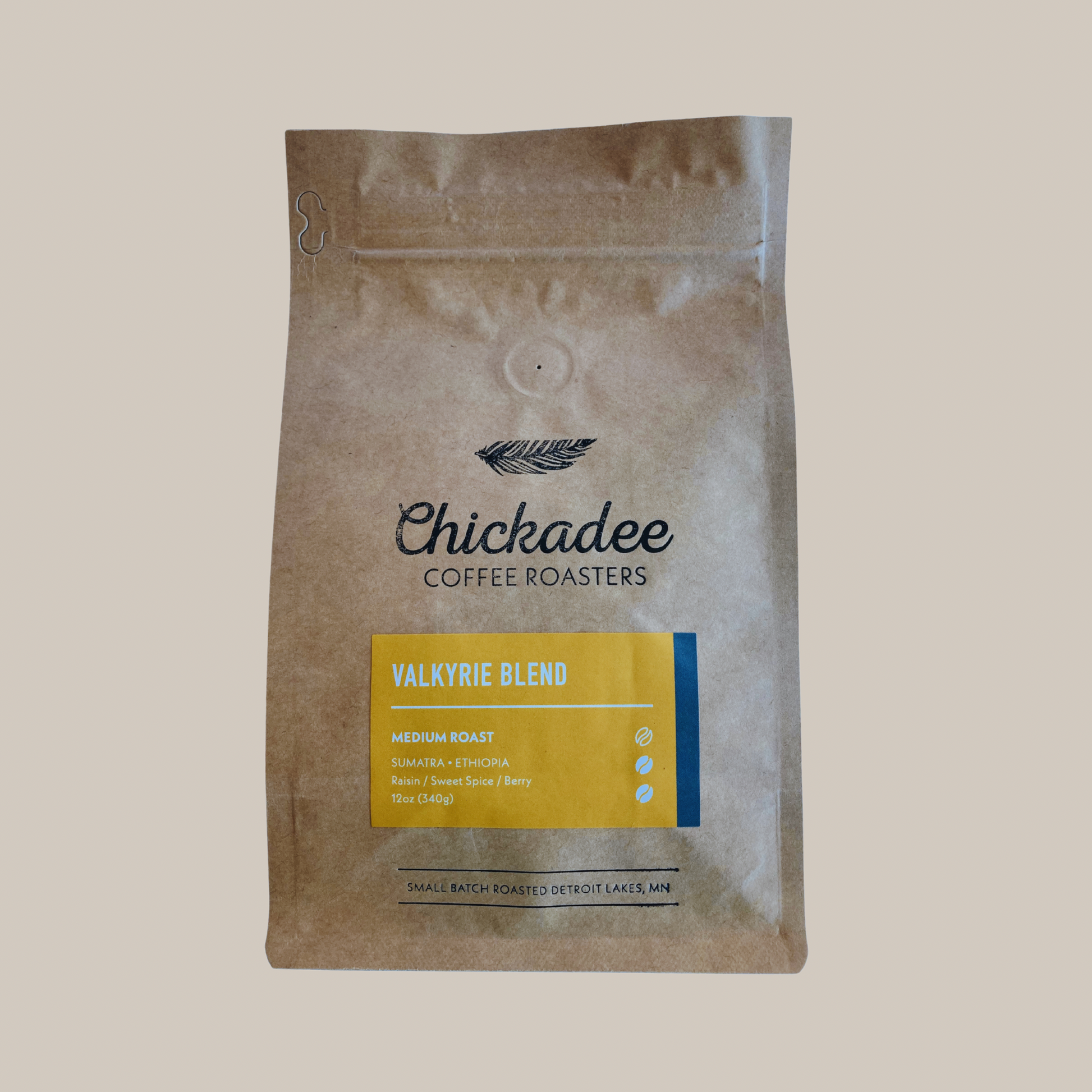 A brown bag of Chickadee Coffee Roasters Valkyrie Blend medium roast coffee with a yellow label, featuring notes of raisin, sweet spice, and berry. This low-acidity blend is small-batch roasted in Detroit Lakes, MN.