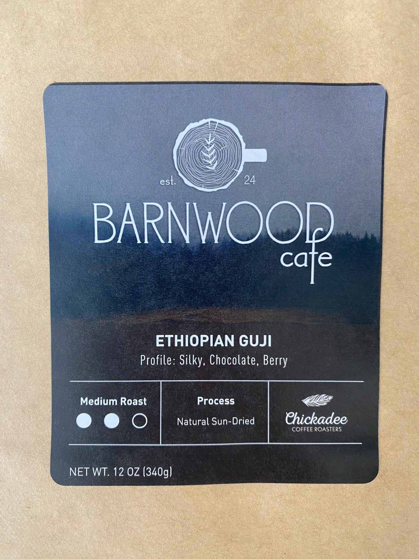 A Barnwood Cafe Blend coffee label by Chickadee Coffee Roasters, featuring silky chocolate and berry notes. This medium roast uses Ethiopian beans, naturally sun-dried. Net weight: 12 oz (340g).