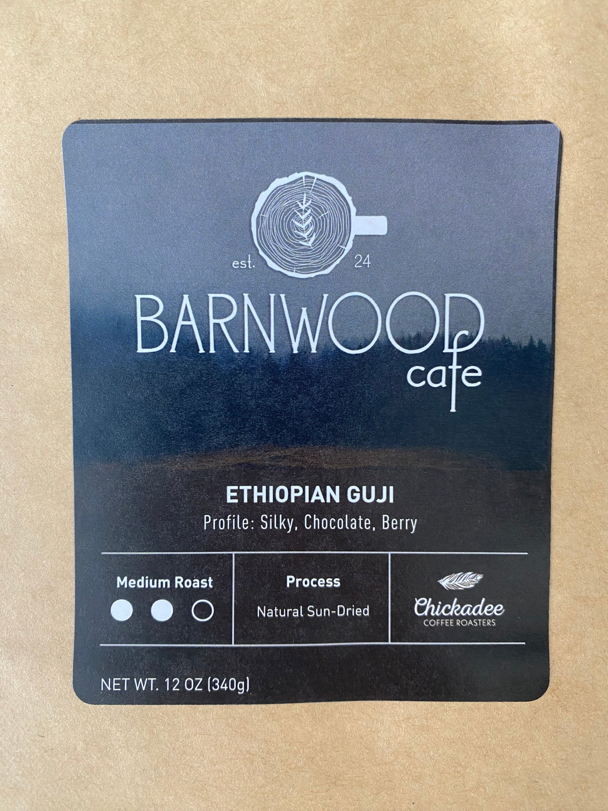 A Barnwood Cafe Blend coffee label by Chickadee Coffee Roasters, featuring silky chocolate and berry notes. This medium roast uses Ethiopian beans, naturally sun-dried. Net weight: 12 oz (340g).